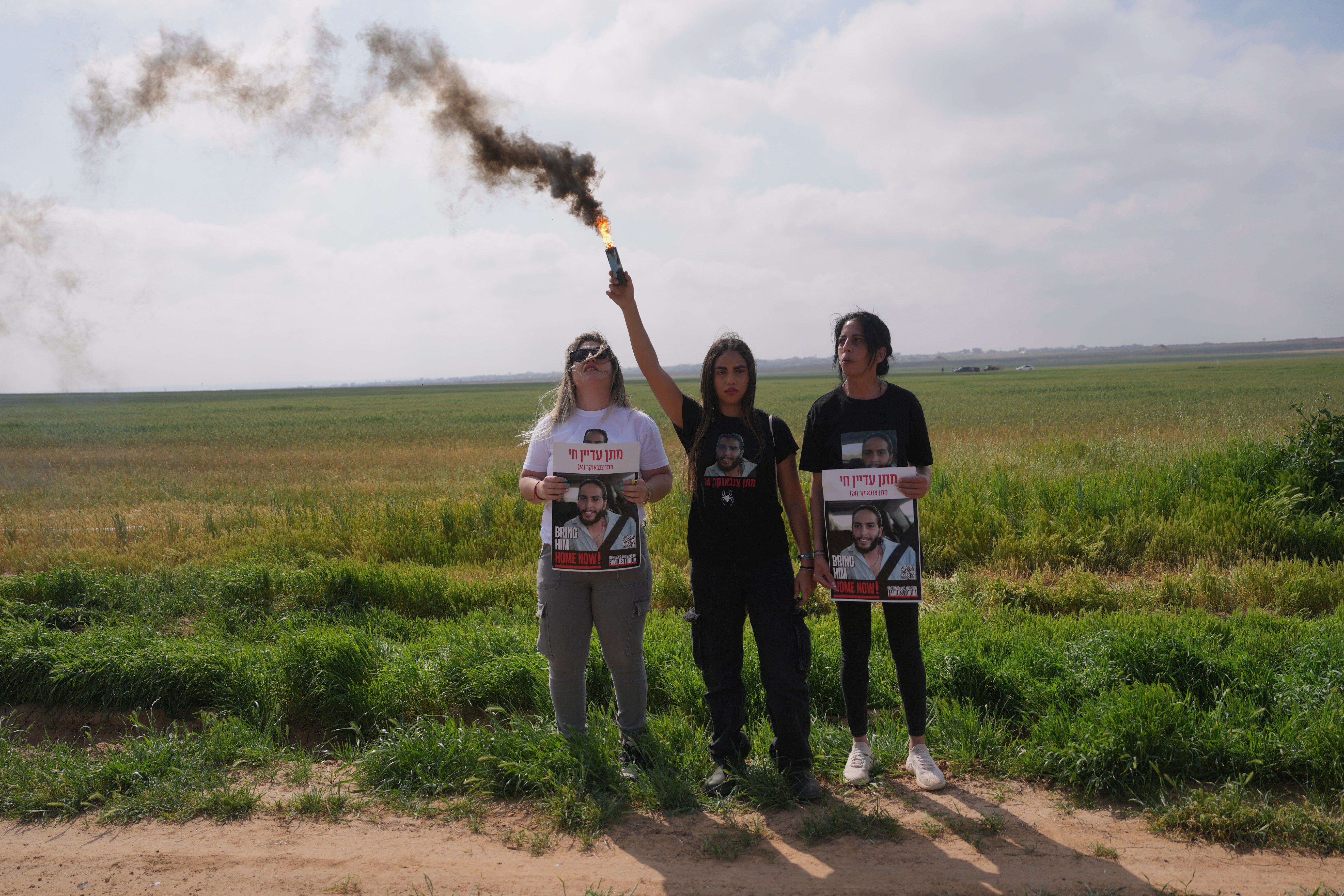 lana Gritzwesky holds a smoke grenade with Einav Zangauker, mother Matan, who is held hostage by Hamas in the Gaza Strip, while escorted by Israeli soldiers, as she and other relatives call for their release and expressing concerns that the resumption of fighting in Gaza puts their loved ones at risk, in southern Israel, Tuesday, March 18, 2025. (AP Photo/Ohad Zwigenberg)