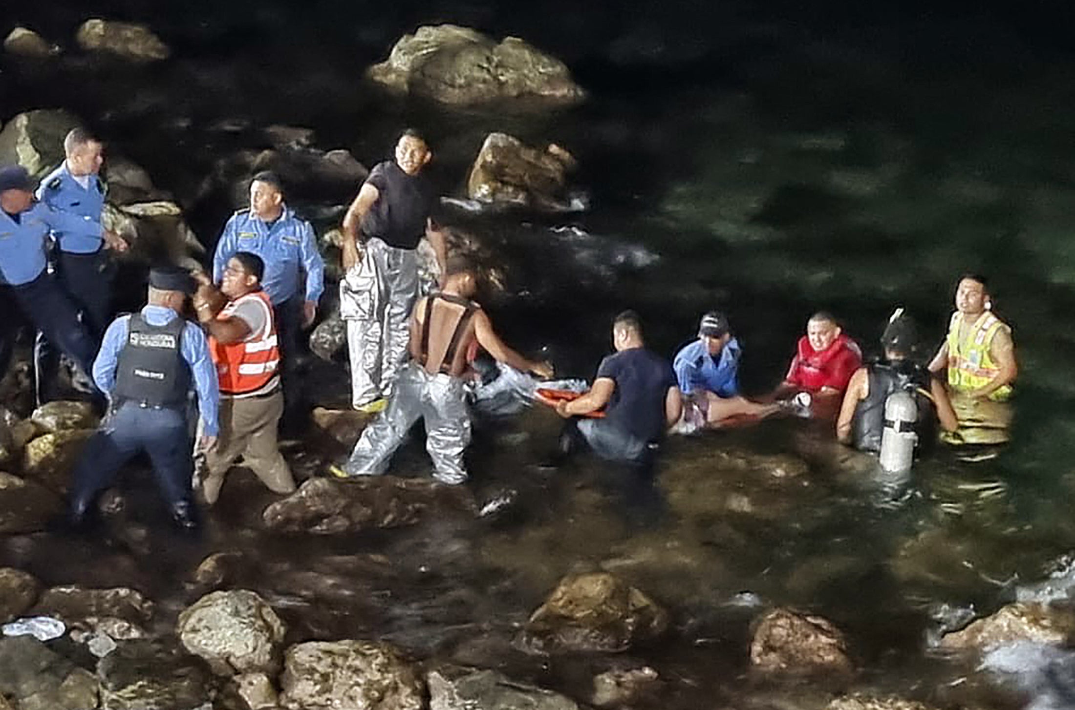 Rescue teams carrying an injured man out of the water after a plane crash in Roatan, Honduras