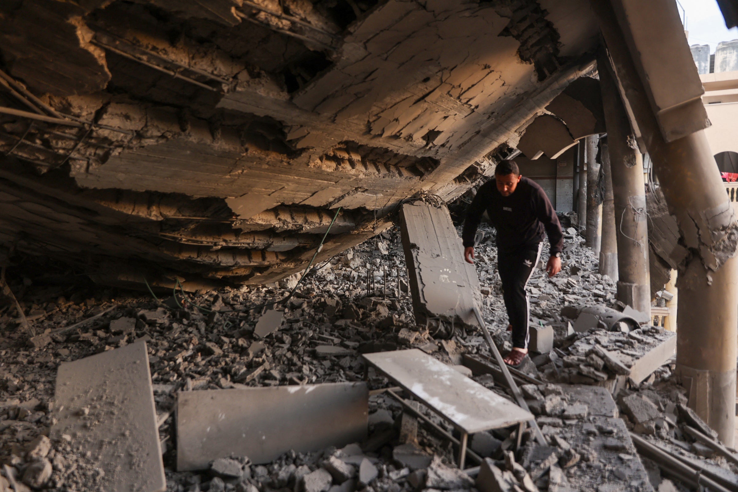 A man walks through the rubble of a destroyed section of a school-turned-camp in Gaza City