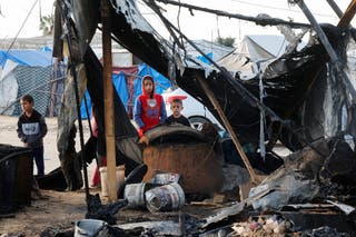 Crianças palestinas inspecionam o local de uma greve israelense em um acampamento de tendas que estão deslocando pessoas deslocadas