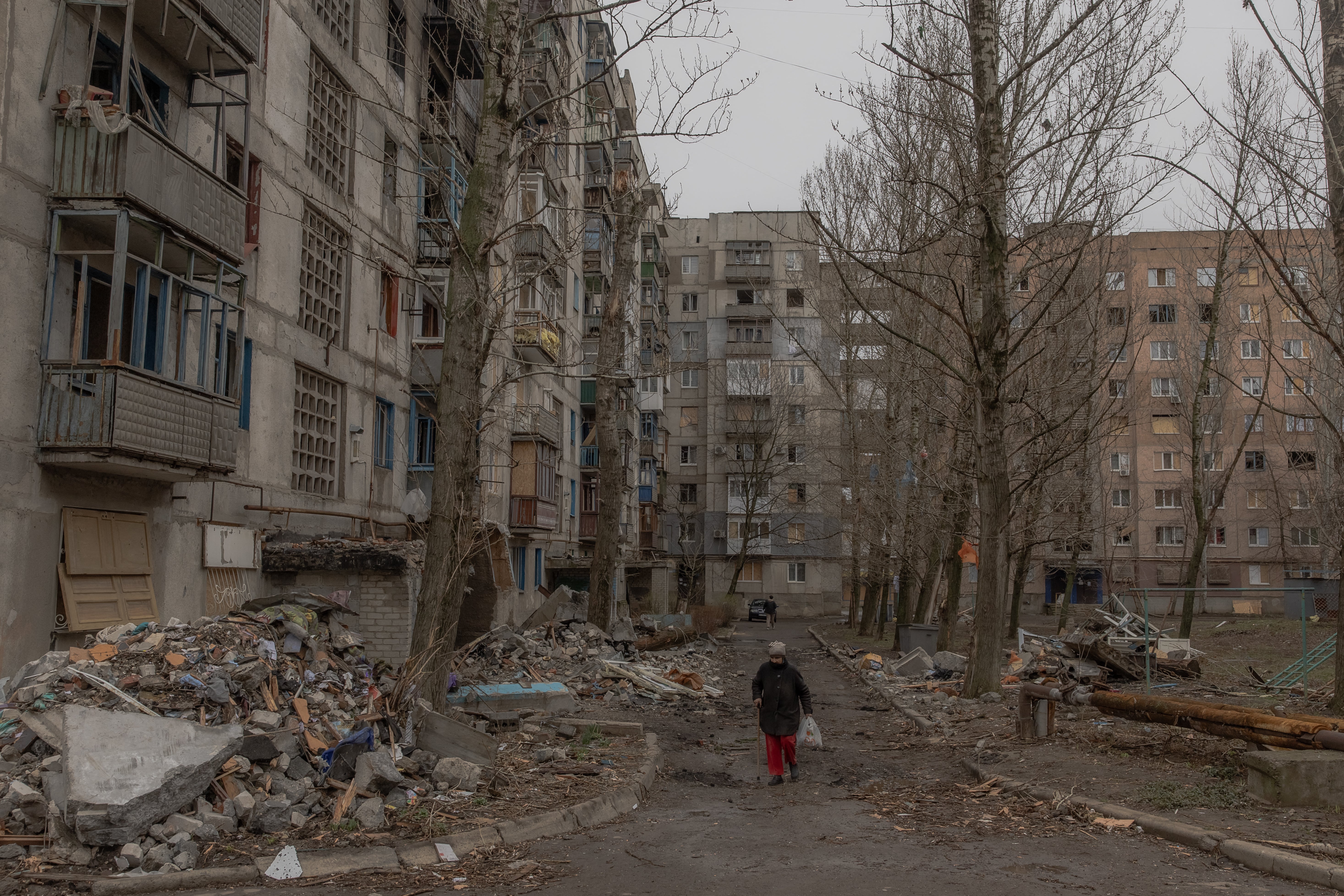 An elderly woman walks past residential buildings that have been heavily damaged by air strikes in Kostyantynivka, in the eastern Donetsk region of Ukraine