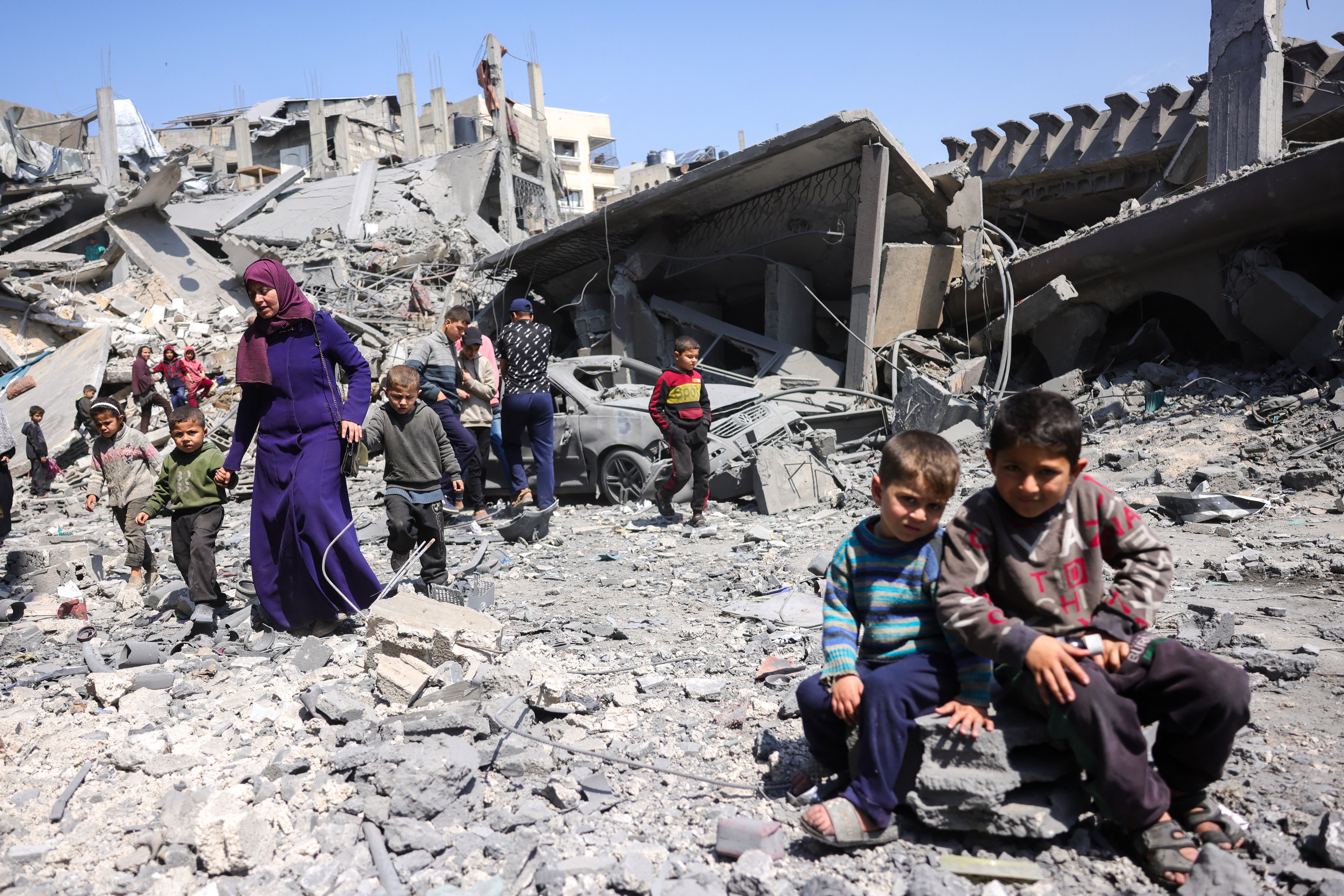 As crianças olham enquanto as pessoas andam em meio aos escombros de um prédio destruído em uma greve de israelenses durante a noite em Jabalia, na faixa do norte de Gaza nesta semana