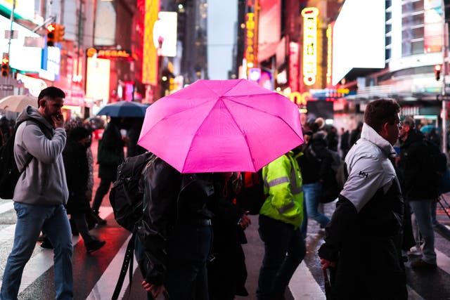 <p>People hold umbrellas as they walk under the rain in a street </p>