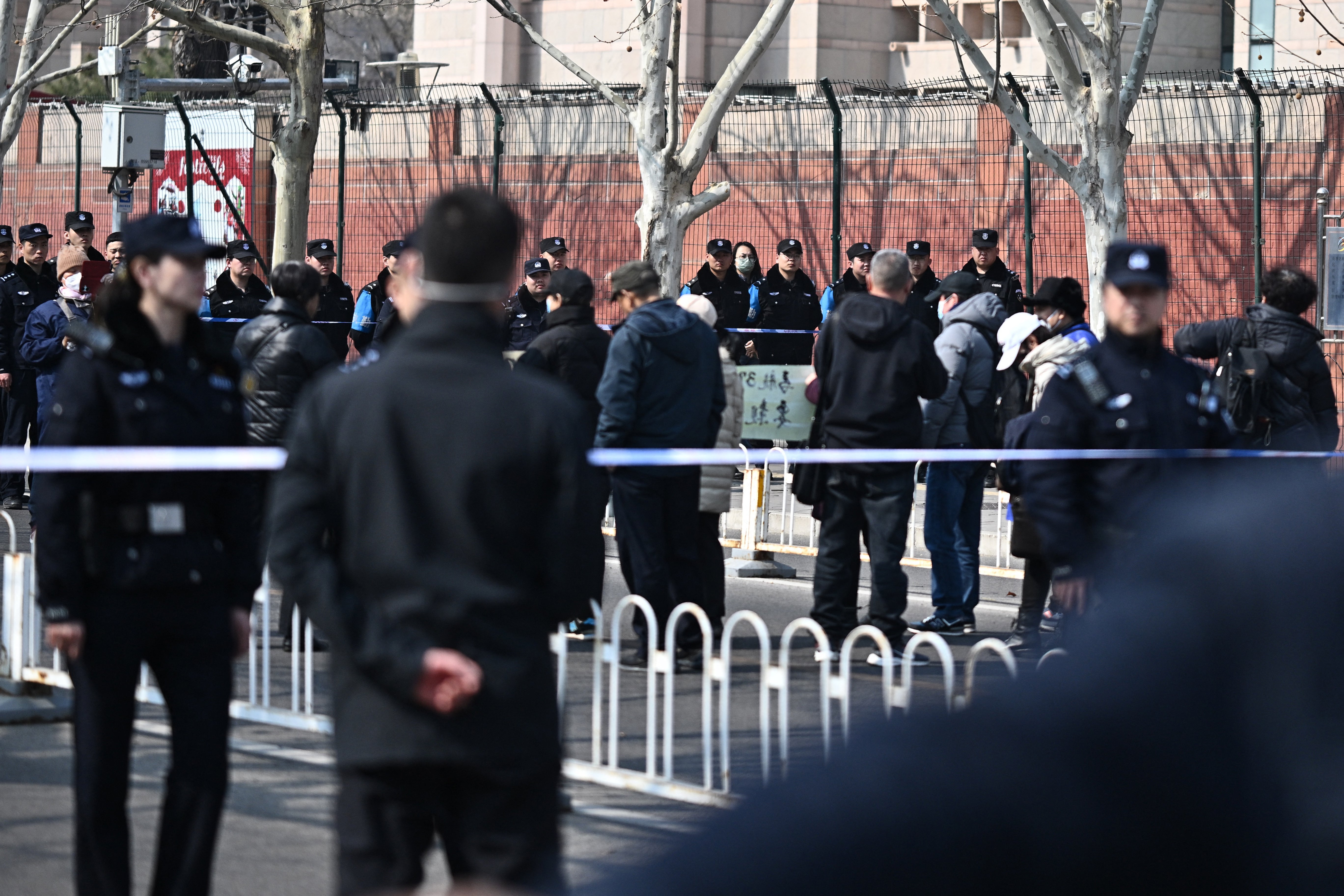 Police look on as relatives of passengers of the missing Malaysia Airlines flight MH370 take part in a demonstration outside the Malaysian embassy in Beijing on 8 March 2025