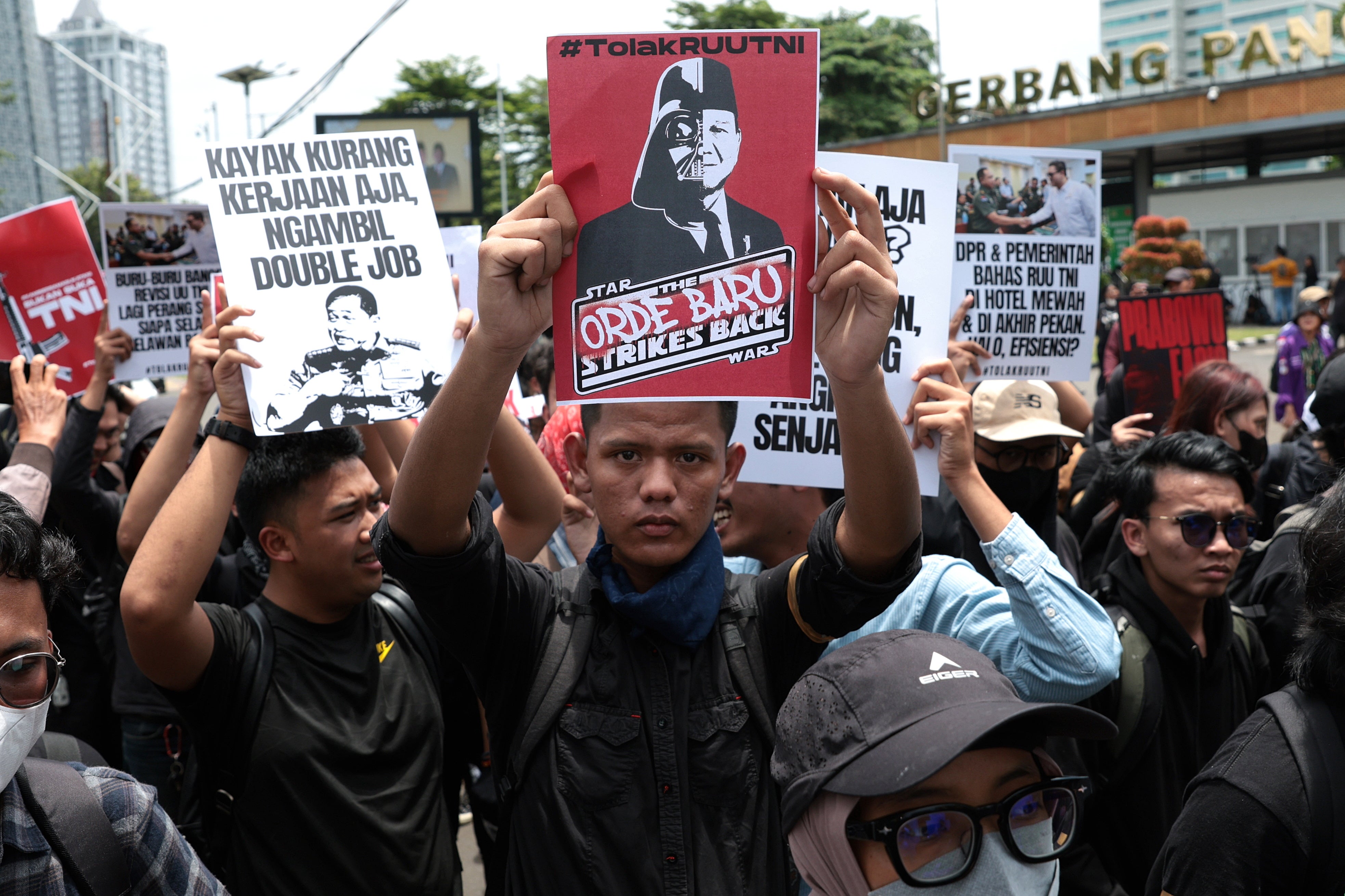 Indonesian activists hold placards during a protest against the revision of the military law in front of the parliament building in Jakarta