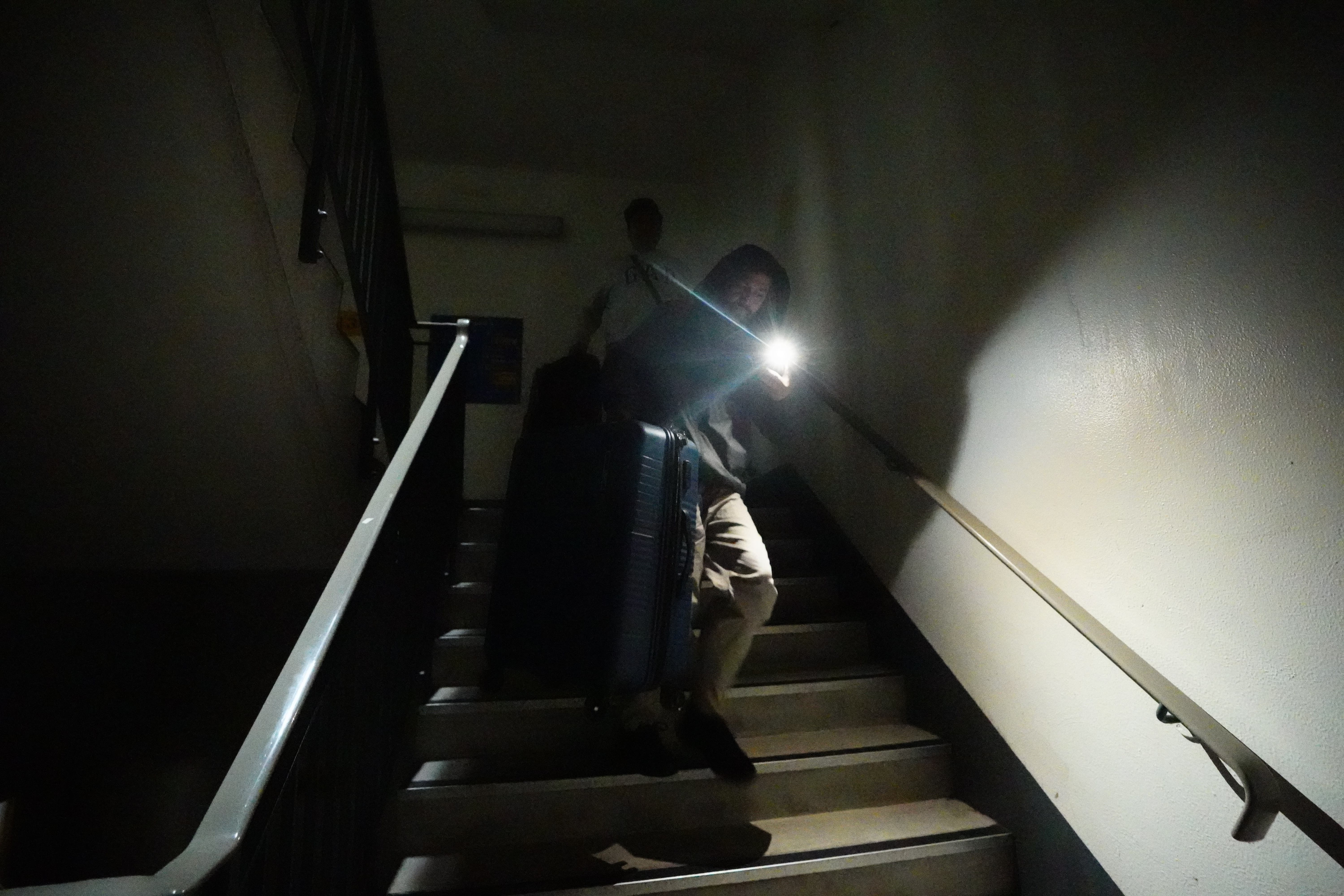 Stranded passengers makes their way down unlit stairs at Heathrow (James Manning/PA)