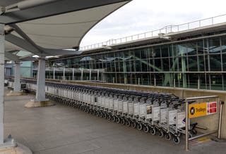 Lines of airport luggage trolleys stand stacked ready for use at Heathrow Terminal 5 on 21 March 2025 in London, England