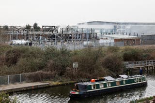 A vessel navigates as smoke rises from the area of an electrical substation, after a fire there wiped out the power at Heathrow International Airport, in Hayes, London, Britain, 21 March 2025