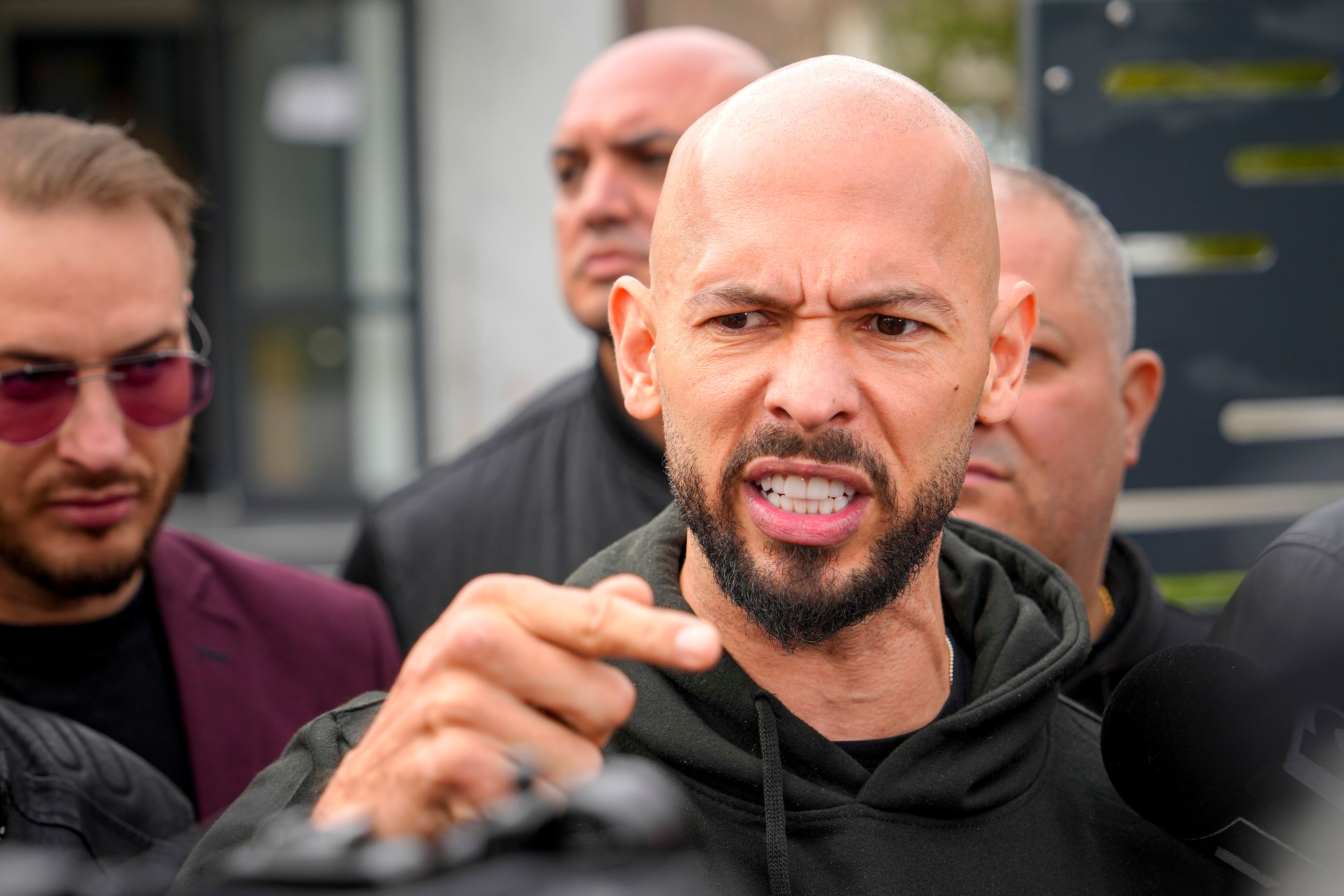 Andrew Tate gestures while speaking to the media after checking in at a police station (Vadim Ghirda/AP)