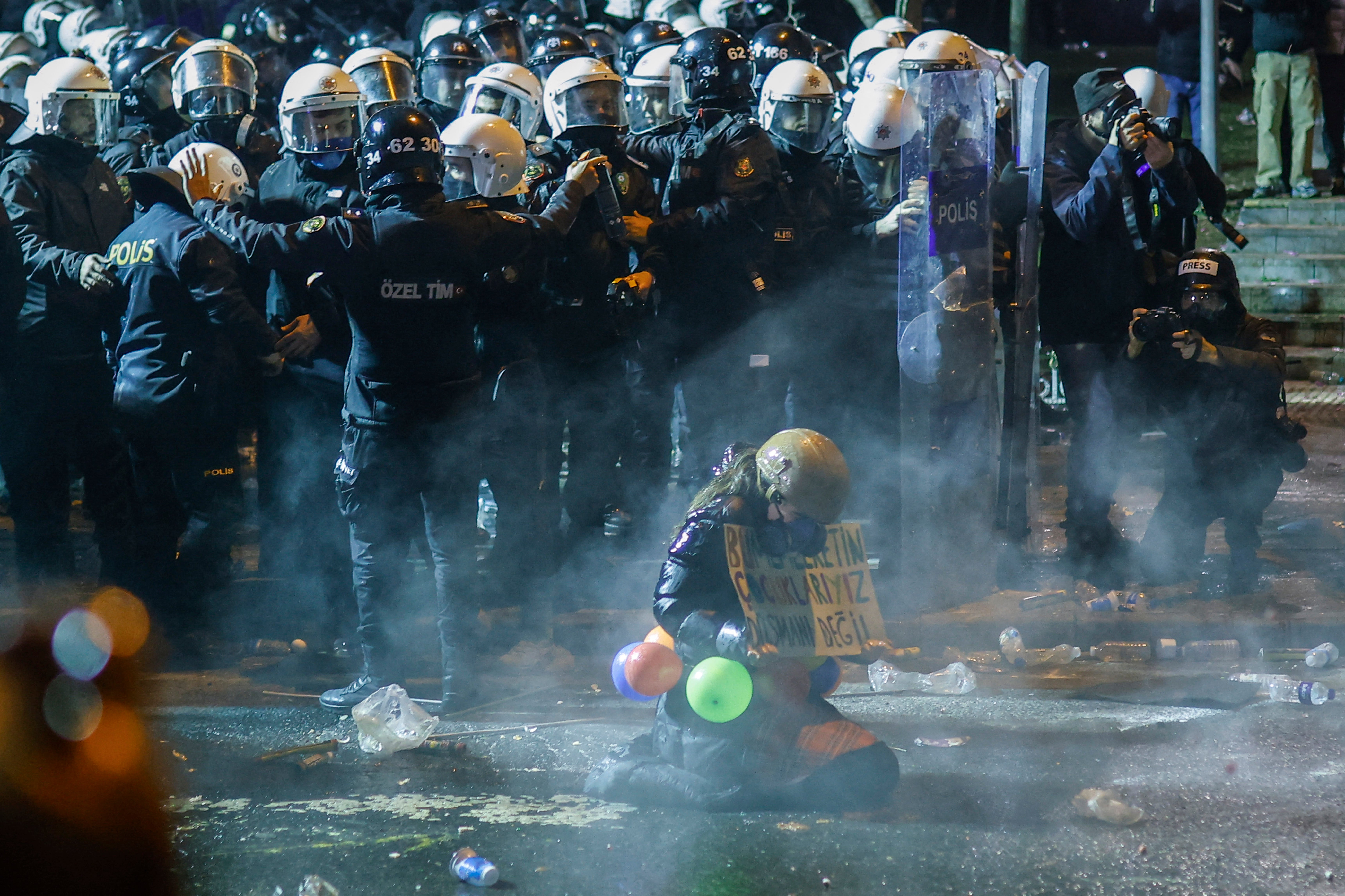 Teargas surrounds a protester holding a placard next to Turkish riot police during a demonstration outside Istanbul’s city hall