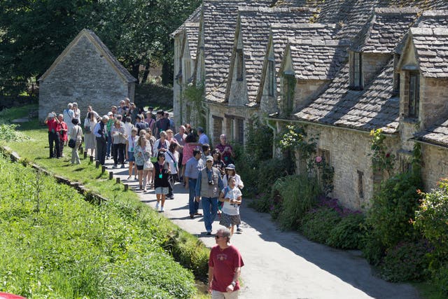 <p>Group of tourists visiting the beautiful and popular Cotswold village of Bibury</p>