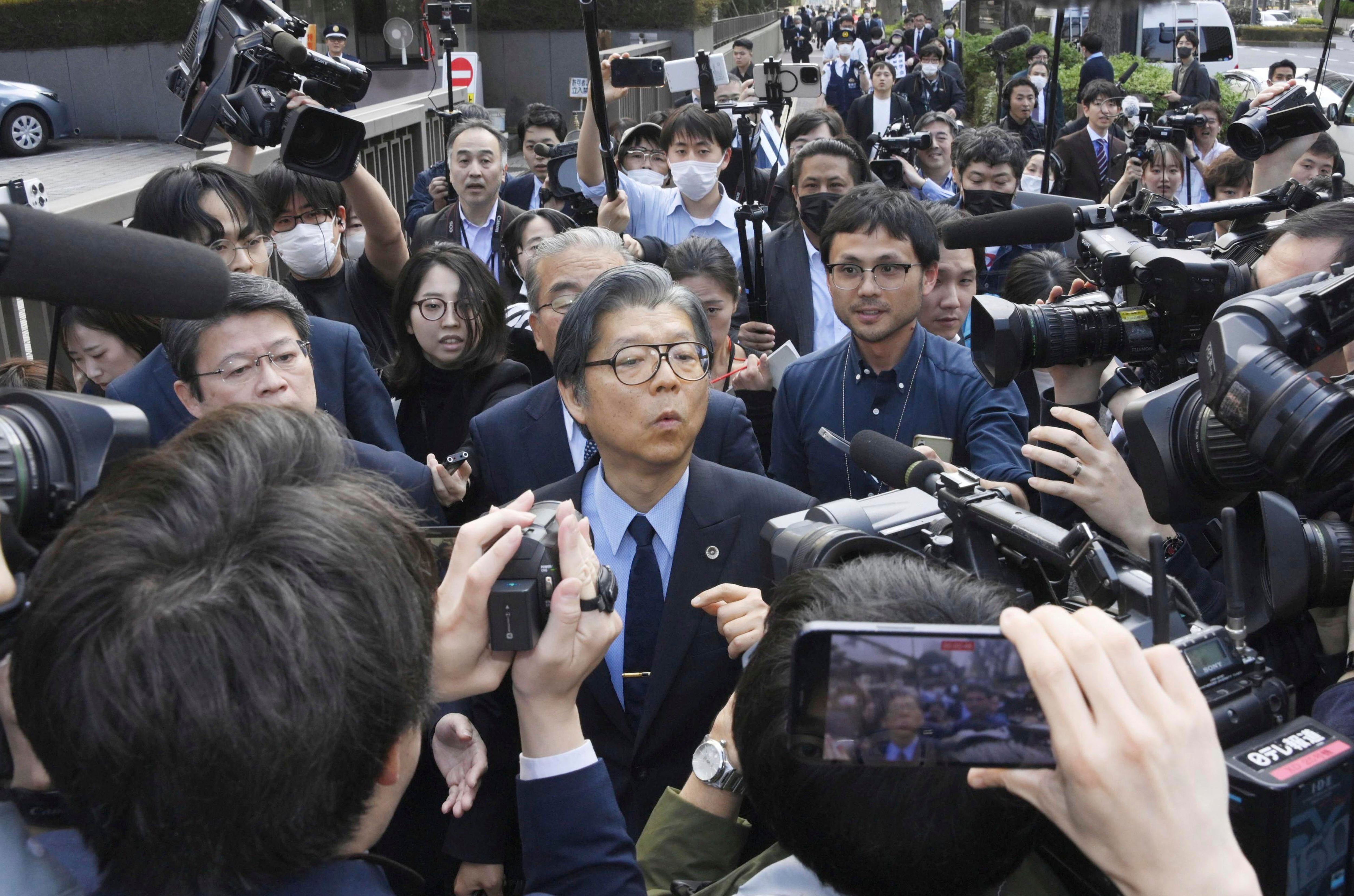 Nobuya Fukumoto, foreground center, a lawyer for the Unification Church, is surrounded by reporters after it’s ordered dissolved by a Tokyo court on Tuesday