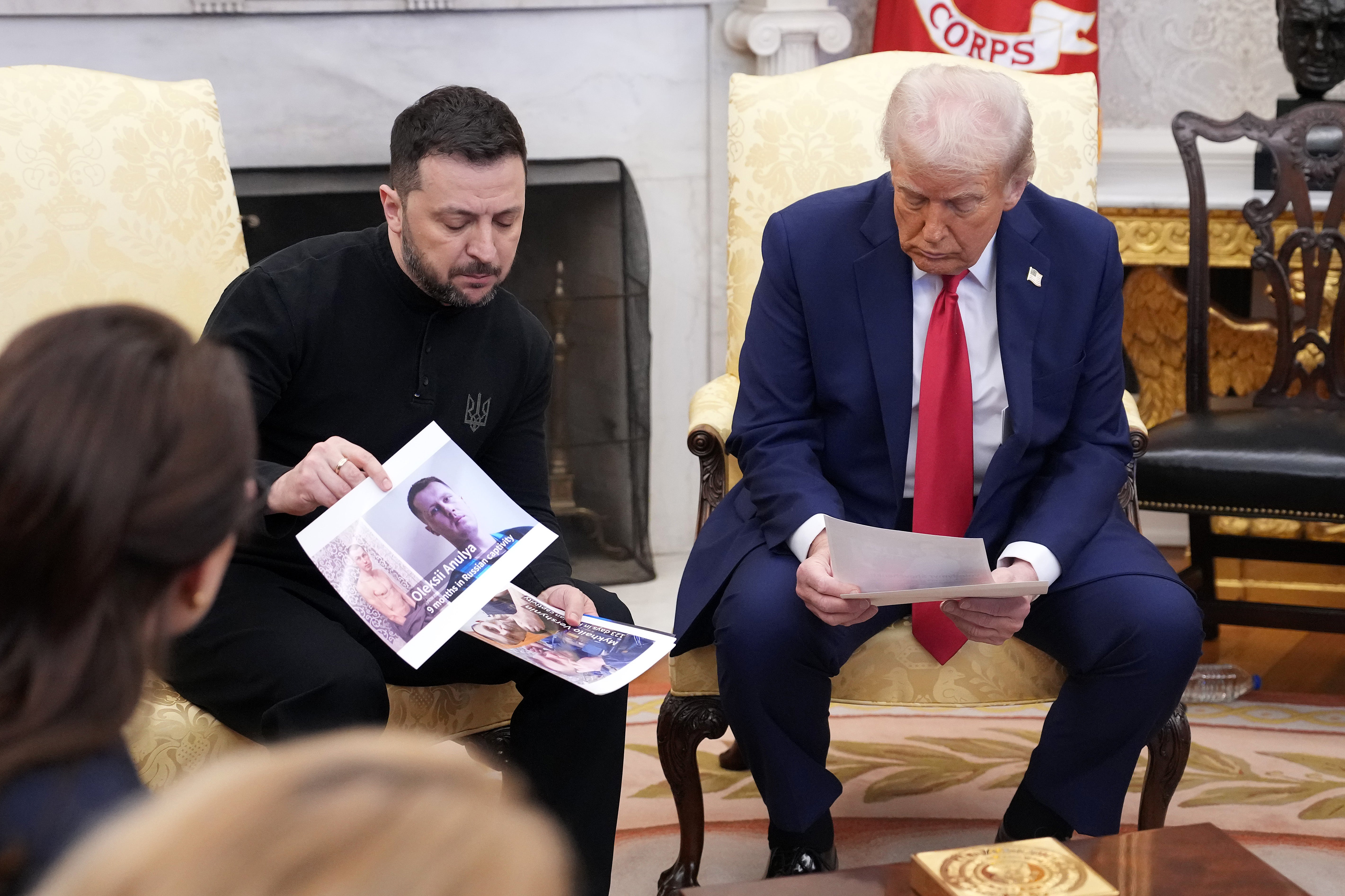 Volodymyr Zelensky holds photos of Ukrainians who were captured by Russian troops