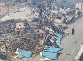 On Wednesday, a man walks near a burnt-out house in a damaged village in Yonggyang, South Korea.