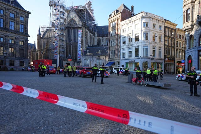 <p>Police officers stand behind a cordoned off area after a stabbing near Dam Square in central Amsterdam</p>