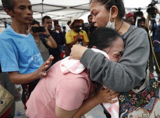 Naruemol Thomglek (C) weeps as she waits for missing family members during a search operation for survivors at the site of a collapsed building following an earthquake in Bangkok