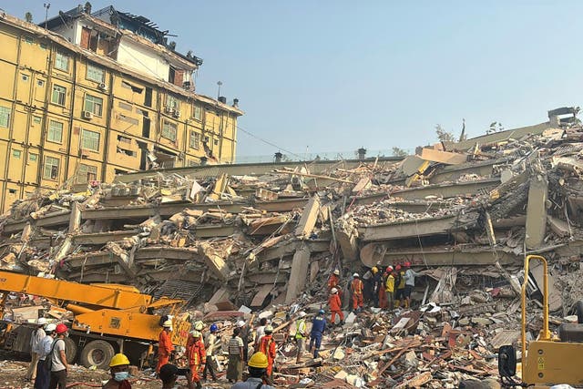 <p>Rescuers sift through the rubble of a collapsed building in Mandalay</p>