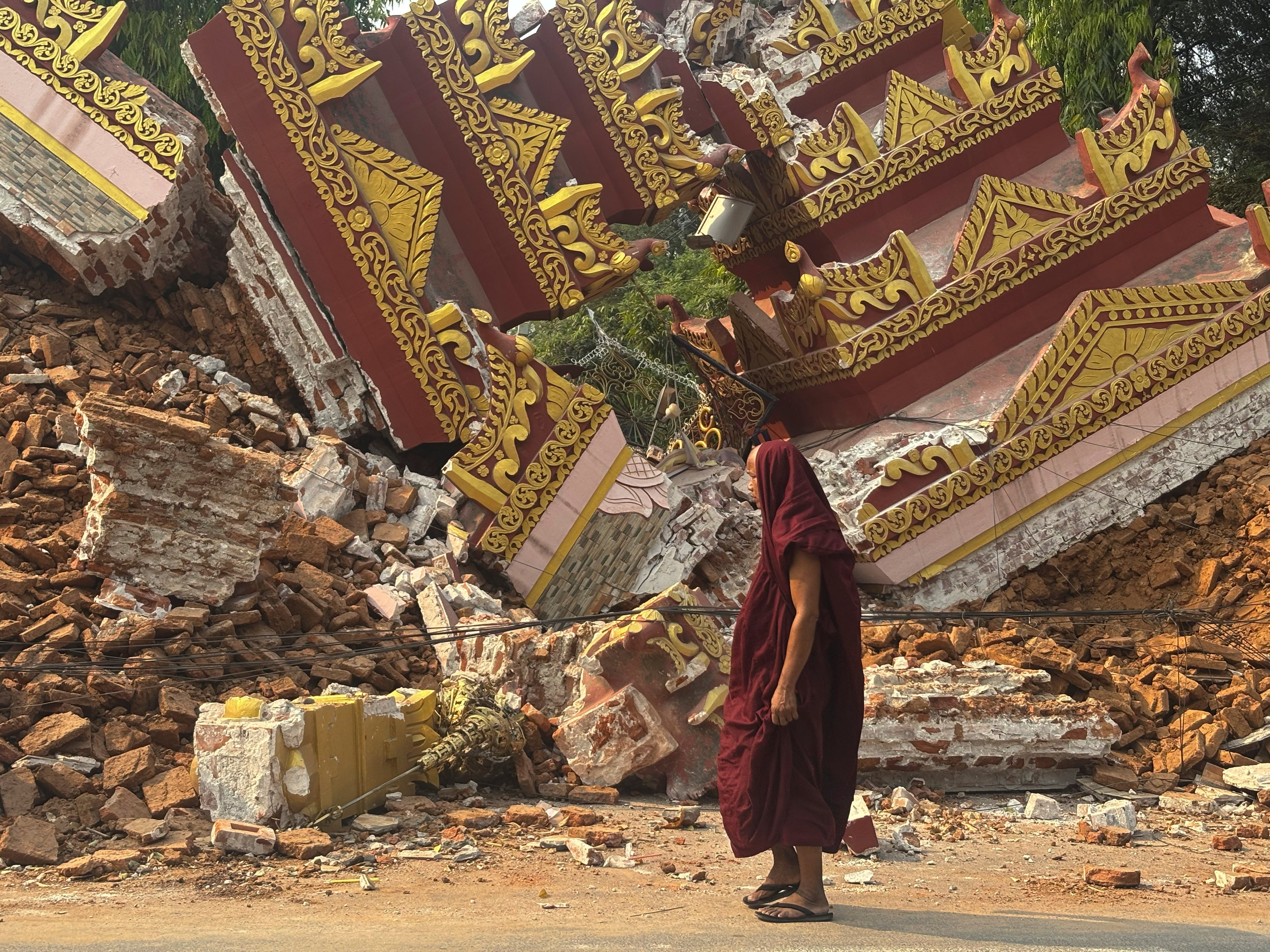 <p>A Buddhist monk walks near a collapsed pagoda after an earthquake in Mandalay </p>