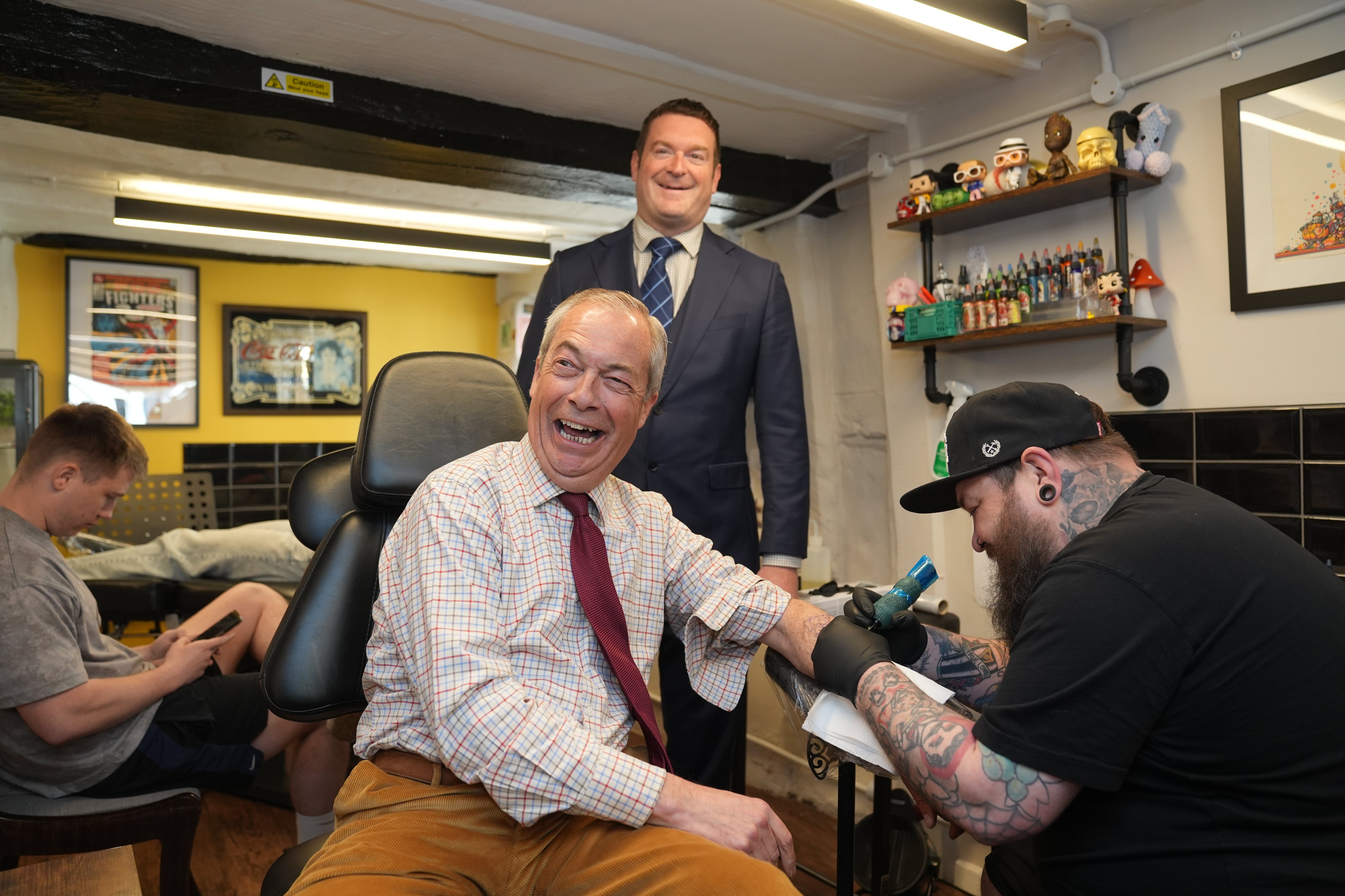Reform UK leader Nigel Farage and Reform UK mayoral candidate Ryan Coogan visit a tattoo parlour during Reform UK's local election campaign