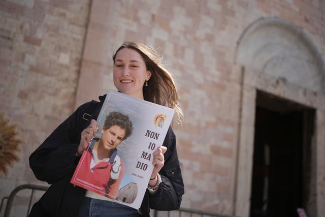 <p>Amelia Simone, an 18-year-old student from Chicago, poses with a photo of Carlo Acutis</p>