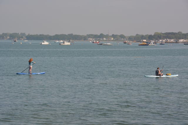 Paddle boarders enjoy the calm conditions during the warm weather in Langstone Harbour in Portsmouth, Hampshire (PA)