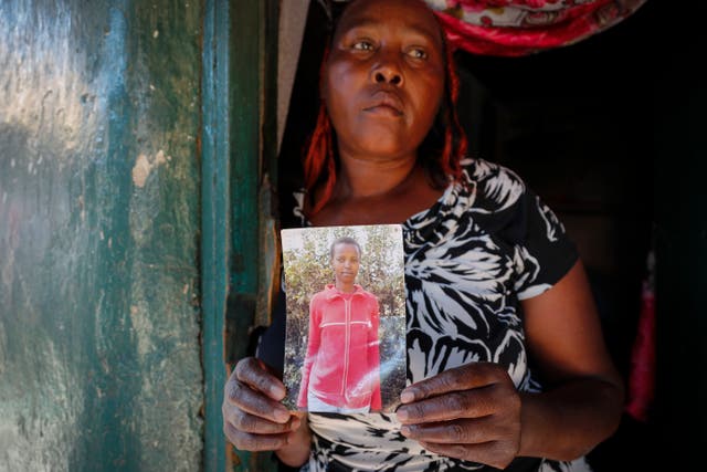 <p>Rose Wanyua Wanjiku holds a photo of her younger sister, Agnes</p>
