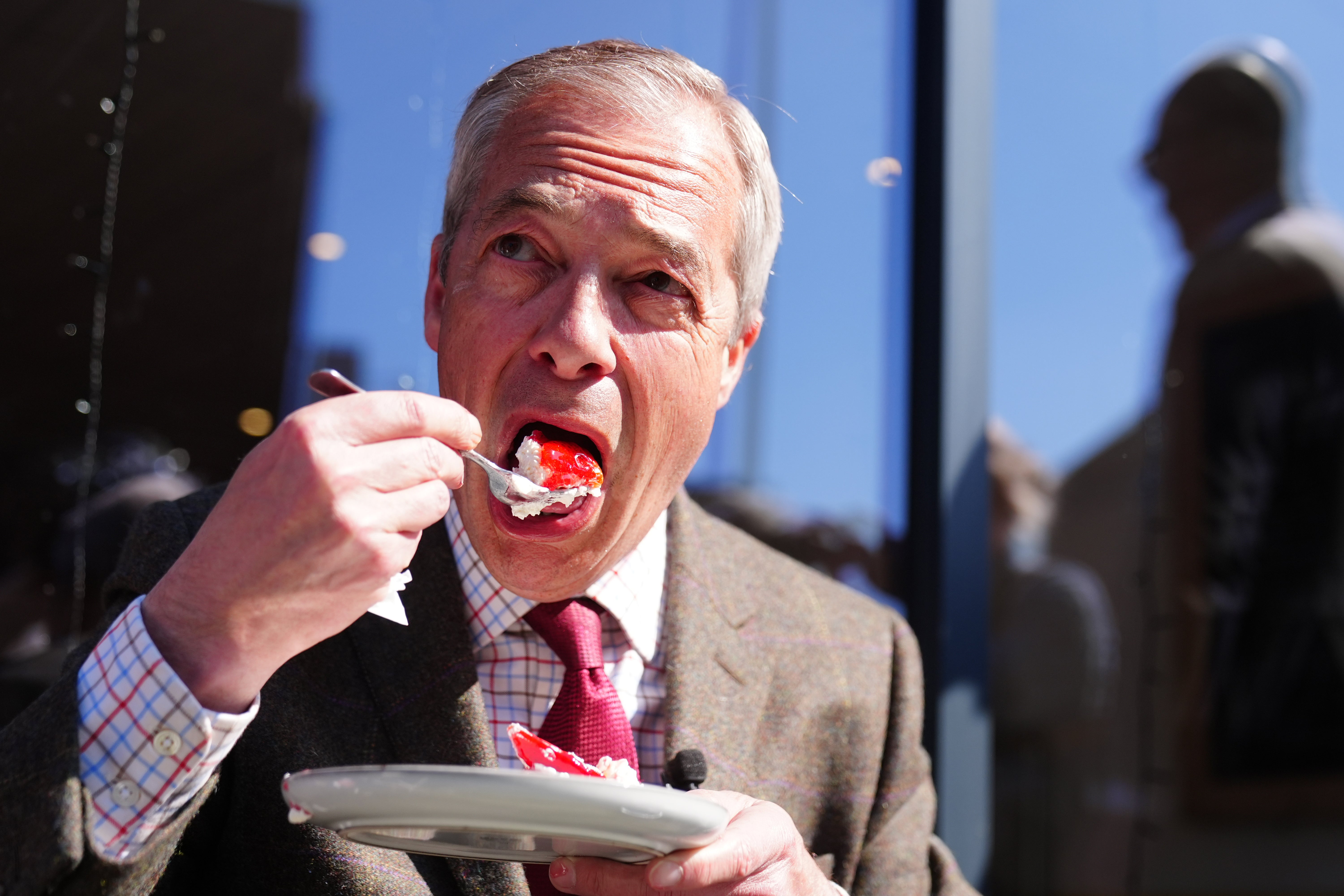 Reform UK leader Nigel Farage eating a cake at a cafe while on the local election campaign trail in Stanley, Durham, on Tuesday
