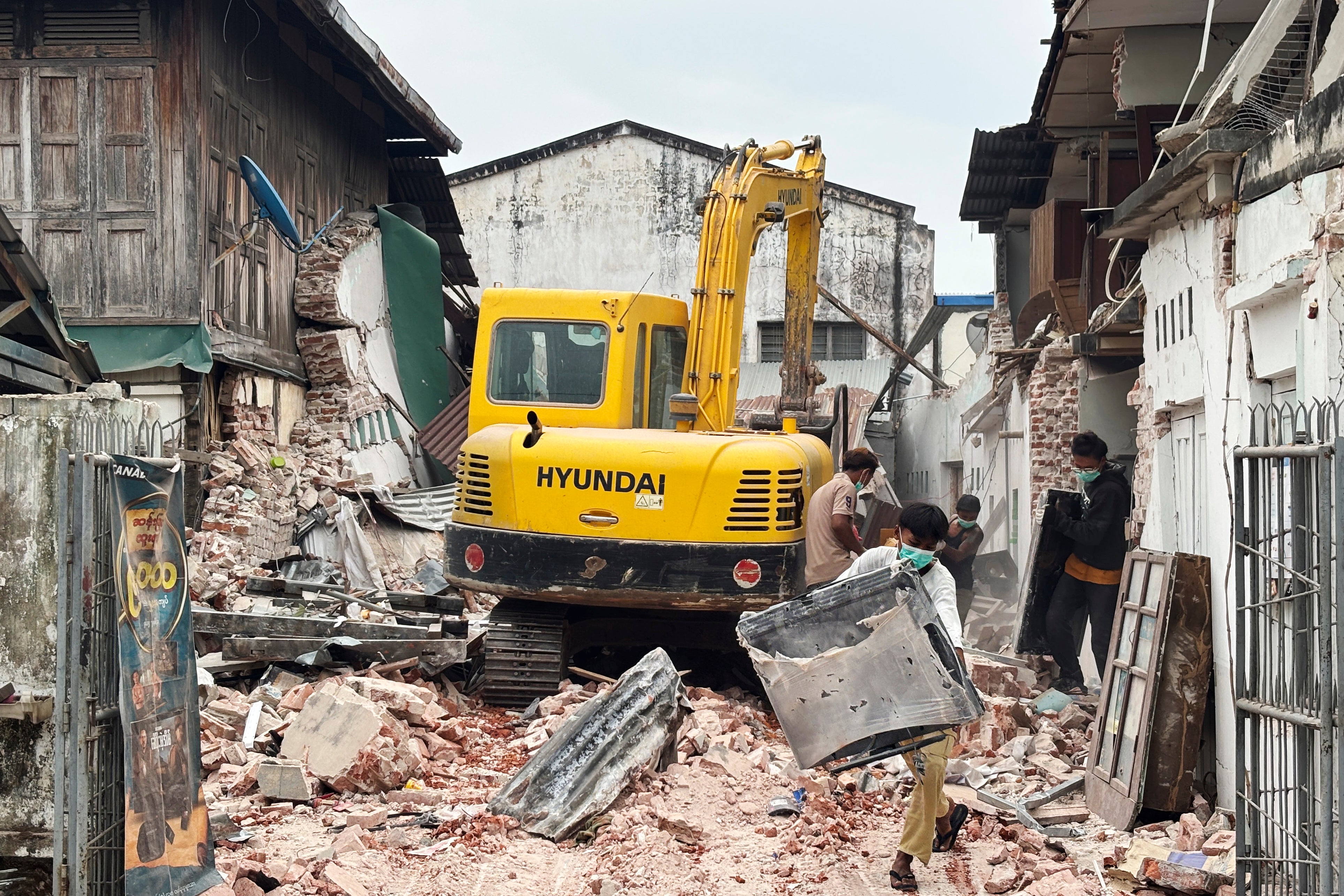 <p>People clean debris from damaged buildings in the aftermath of an earthquake on 28 March, in Naypyitaw, Myanmar</p>