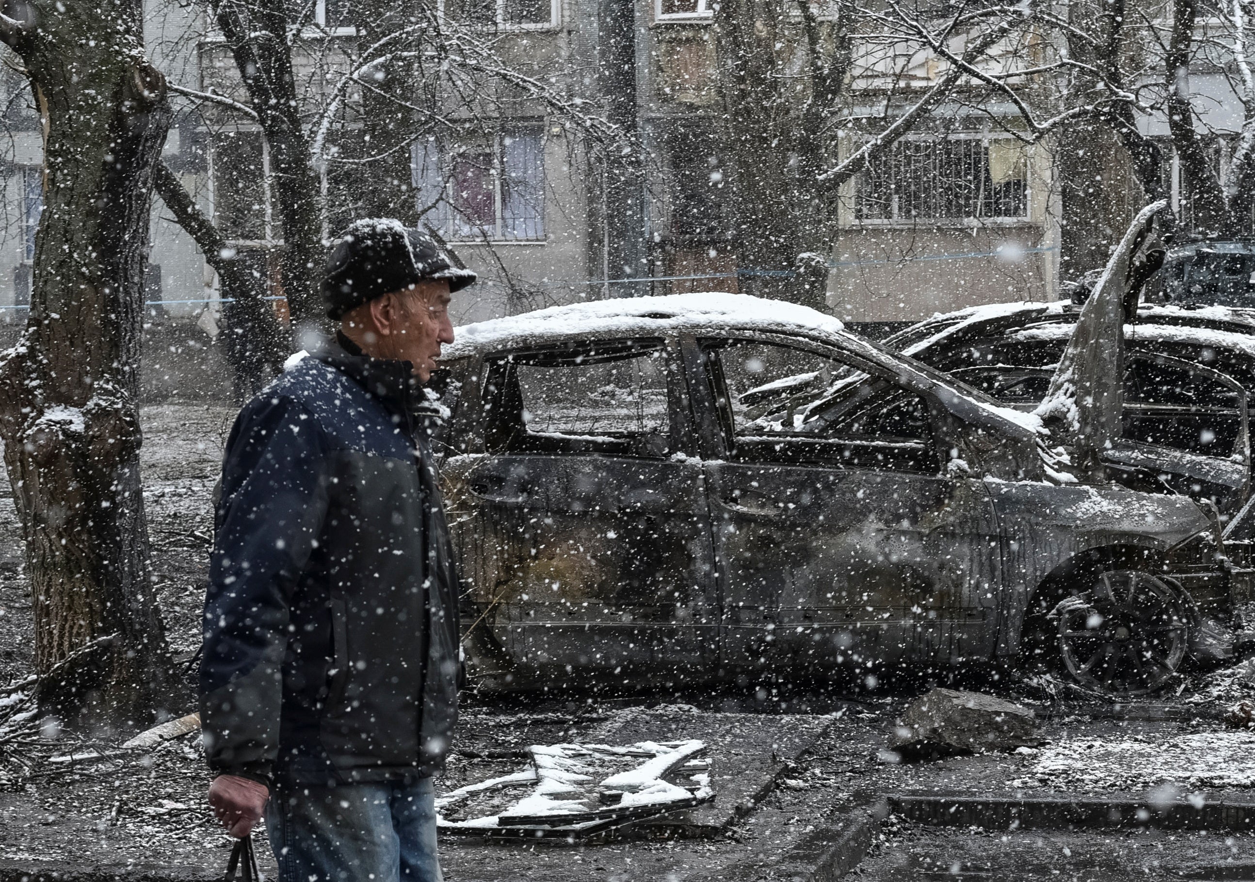 A local passes by burned cars at the site of a Russian drone strike in Dnipro