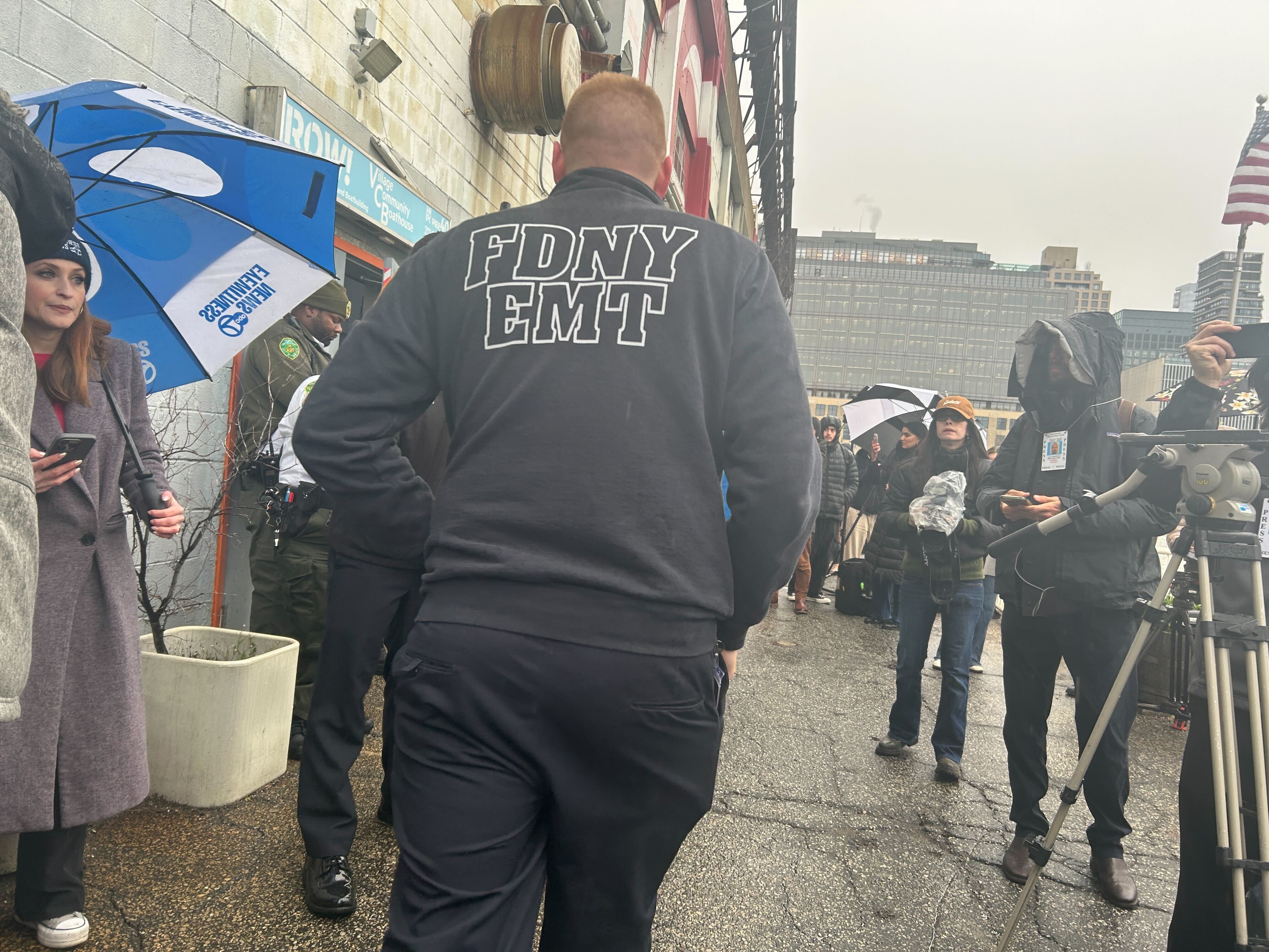 A New York City Fire Department EMT walks among the throng of media gathered at Pier 40 in New York City after a helicopter plunged into the Hudson River on April 10, 2025