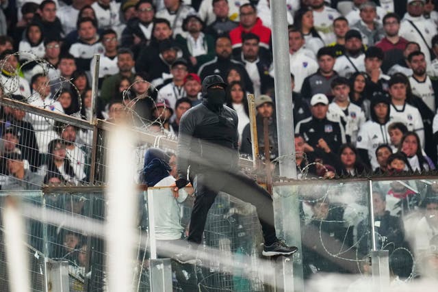 <p>A fan climbs on a glass panel in the stands during a Copa Libertadores Group E soccer match between Chile's Colo Colo and Brazil's Fortaleza at Monumental Stadium in Santiago, Chile, Thursday, April 10, 2025</p>