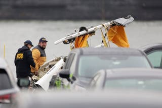 Investigators with the National Transportation Safety Board investigate the wreckage of a siteseeing helicopter, Friday, April 11, 2025, that crashed into the Hudson River a day earlier in Jersey City, N.J. (AP Photo/Adam Hunger)