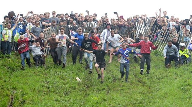<p>Competitors take part in the annual unofficial cheese rolling at Cooper’s Hill in Brockworth, Gloucestershire (Ben Birchall/PA)</p>