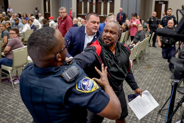 <p>A protester resists being removed by an Acworth Police officer as Republican Representative from Georgia Marjorie Taylor Greene participates in her Cobb County Town Hall at the Acworth Community Center in Acworth, Georgia on April 15</p>