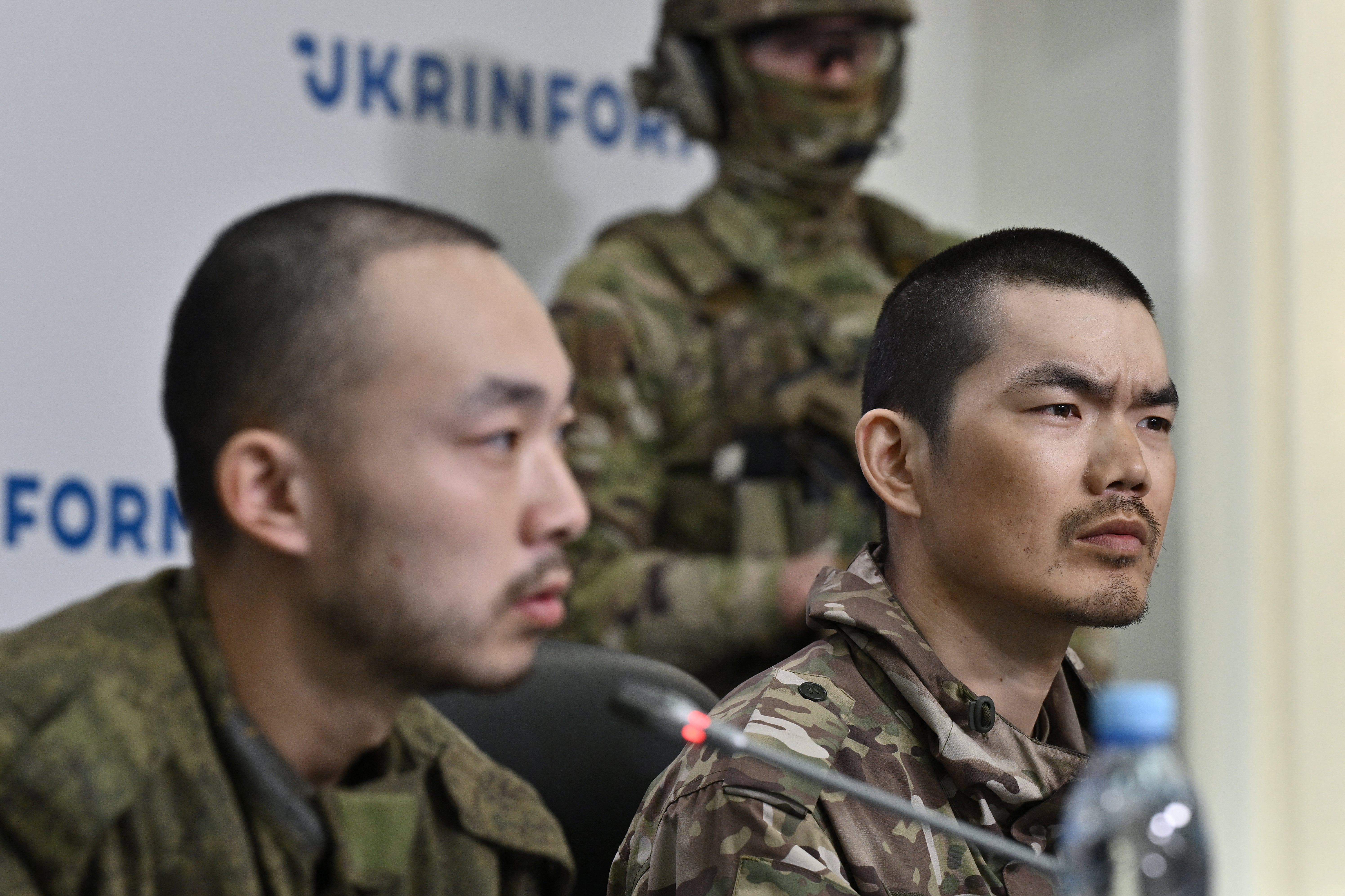 Chinese prisoners of war under armed guard Zhang Renbo (L) and Wang Guangjung (R) look on during a press conference in Kyiv