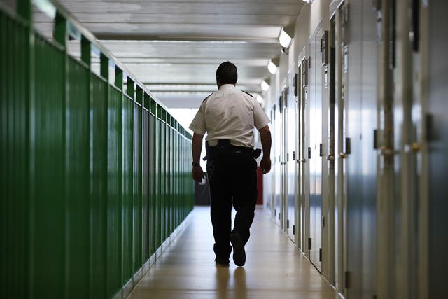 <p>A prison guard walks through a cell area at HMP Berwyn</p>