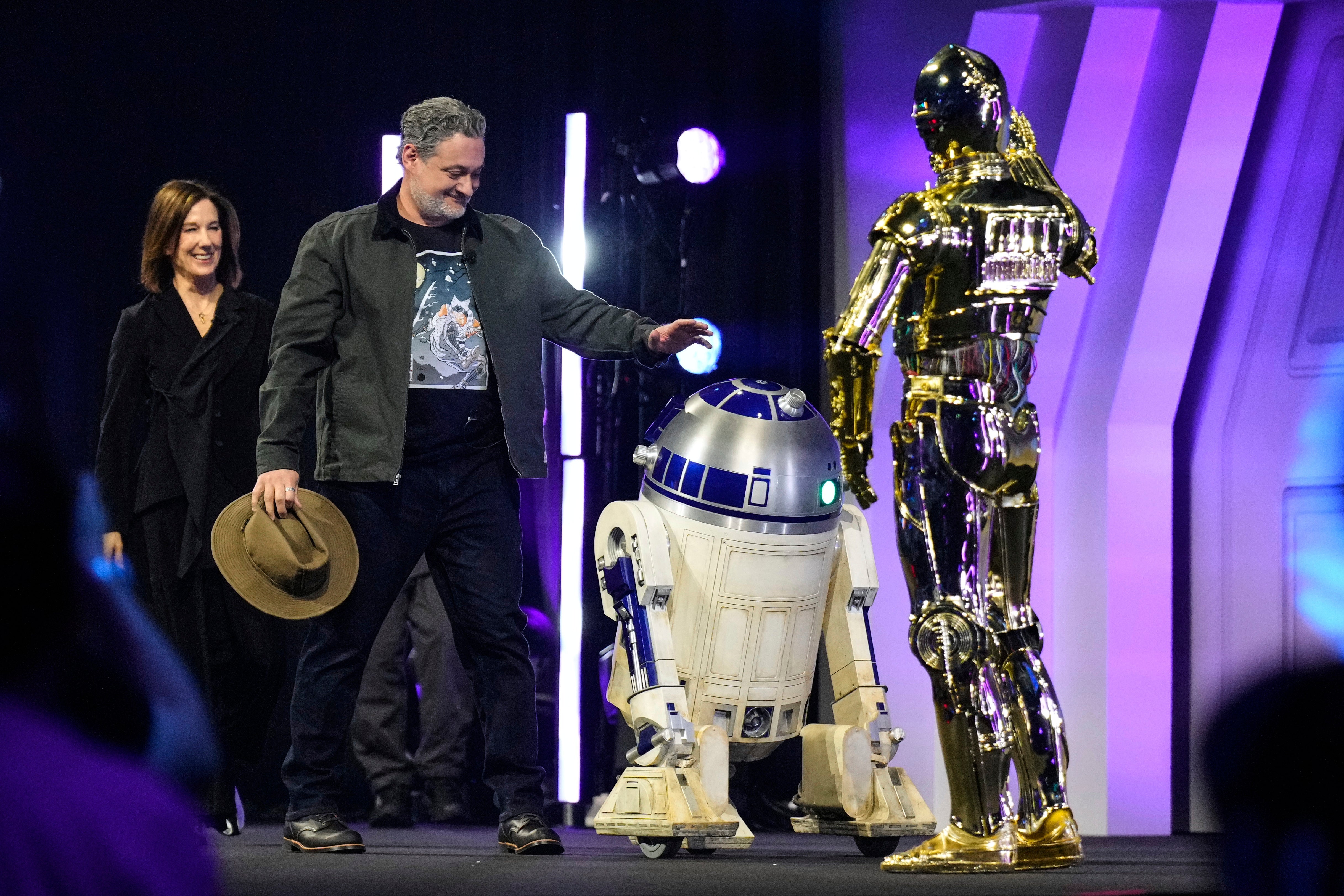 <p>Kathleen Kennedy, left, and Dave Filoni are welcomed by R2-D2 and C-3PO during a Star Wars convention in Japan</p>