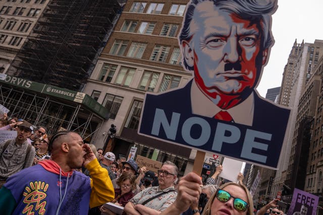 <p>A person shouts next to an image of President Donald Trump as people take part in a protest organised to 'Protect Migrants, Protect the Planet' on April 19, 2025 in New York City</p>