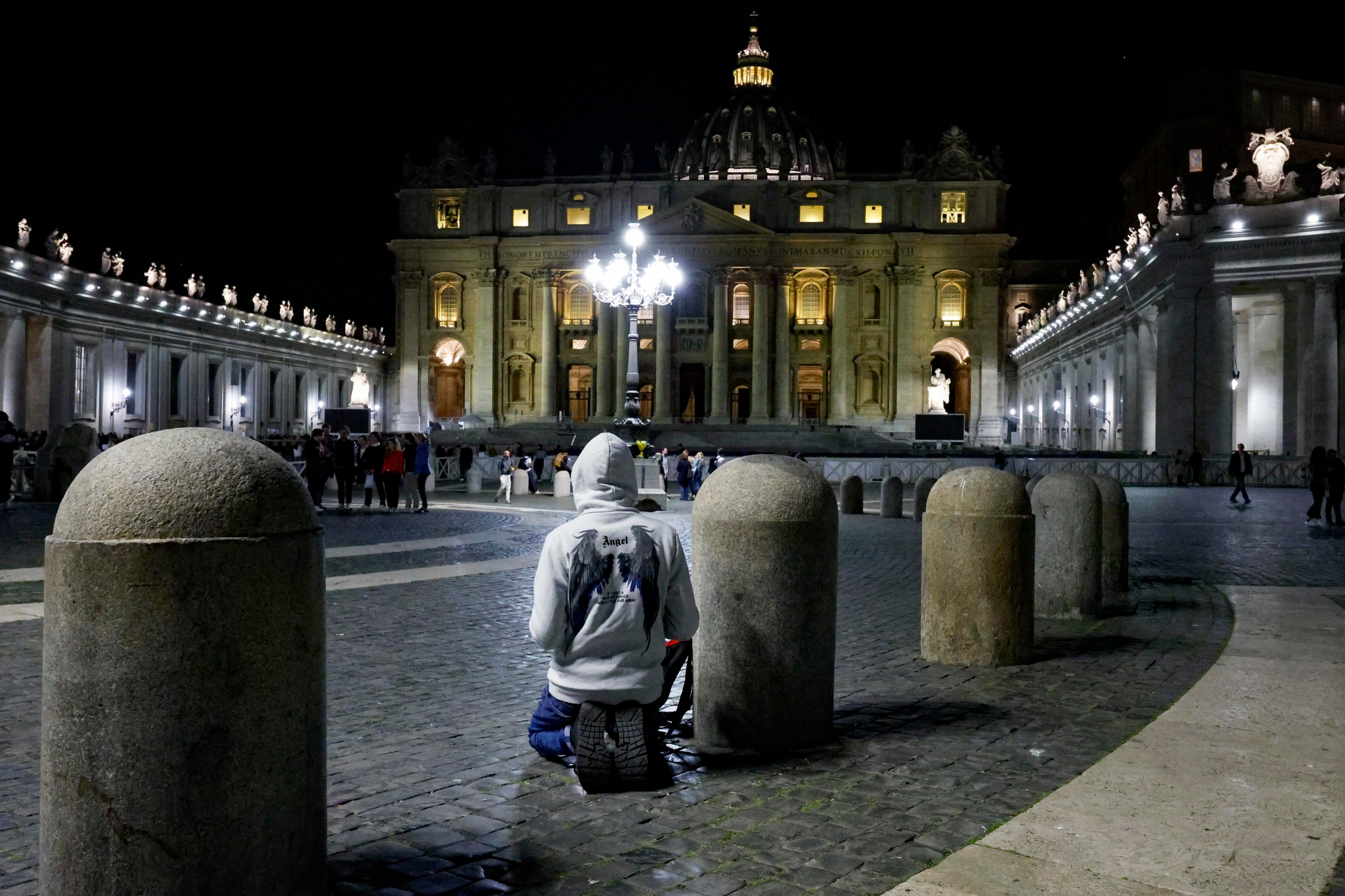 A faithful prays in St. Peter's Square as people gather following the death of Pope Francis, in Vatican City, Italy