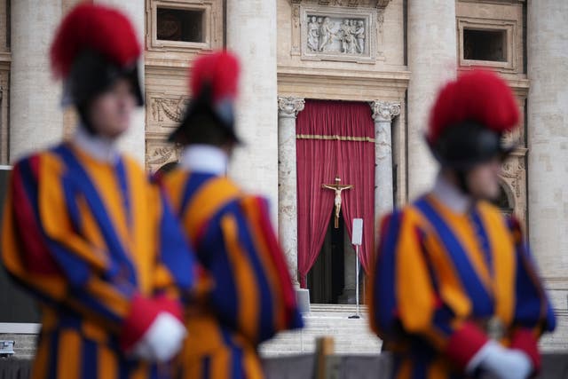 <p>Vatican Swiss Guards at the entrance to St Peter’s Basilica as the pope’s coffin is transported there</p>