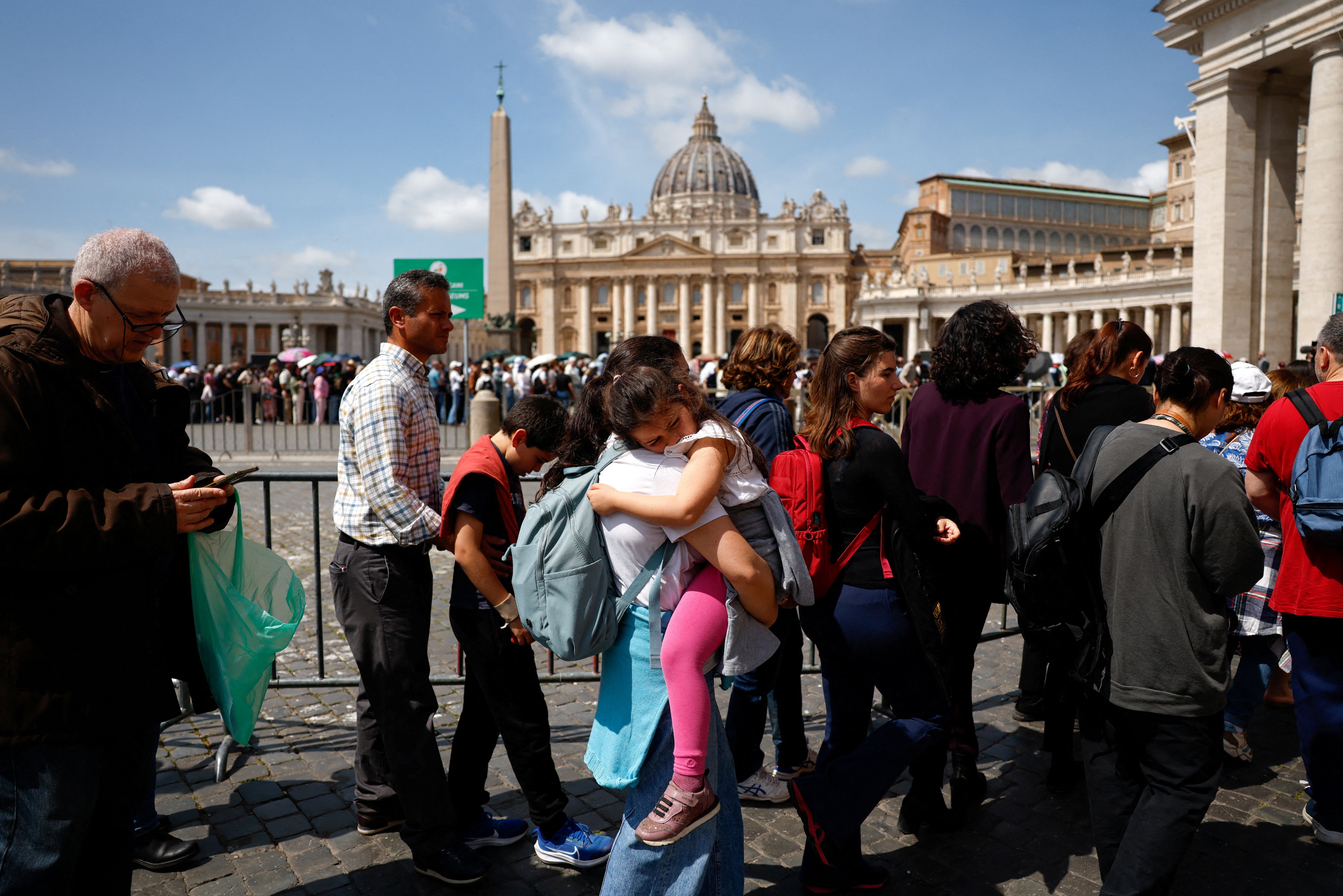 A woman with a child queues to enter St. Peter's Basilica