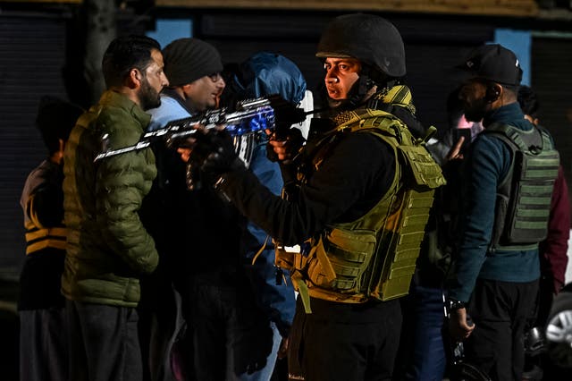 <p>Indian soldiers speak with tourists near Pahalgam in the wake of the attack on 22 April 2025</p>