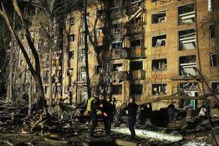 Ukrainian police officers stand near a damaged building