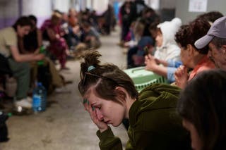 A woman sits in a school basement being used as a shelter after a Russian airstrike on a residential neighborhood in Kyiv