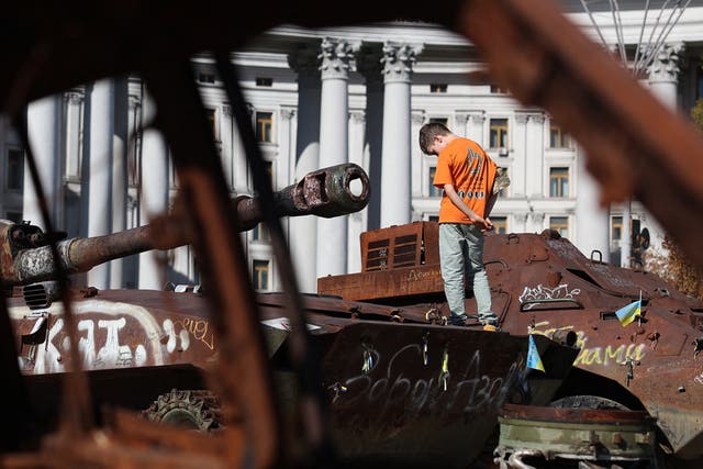 <p>A boy stands on a destroyed Russian tank in central Kyiv, Ukraine</p>