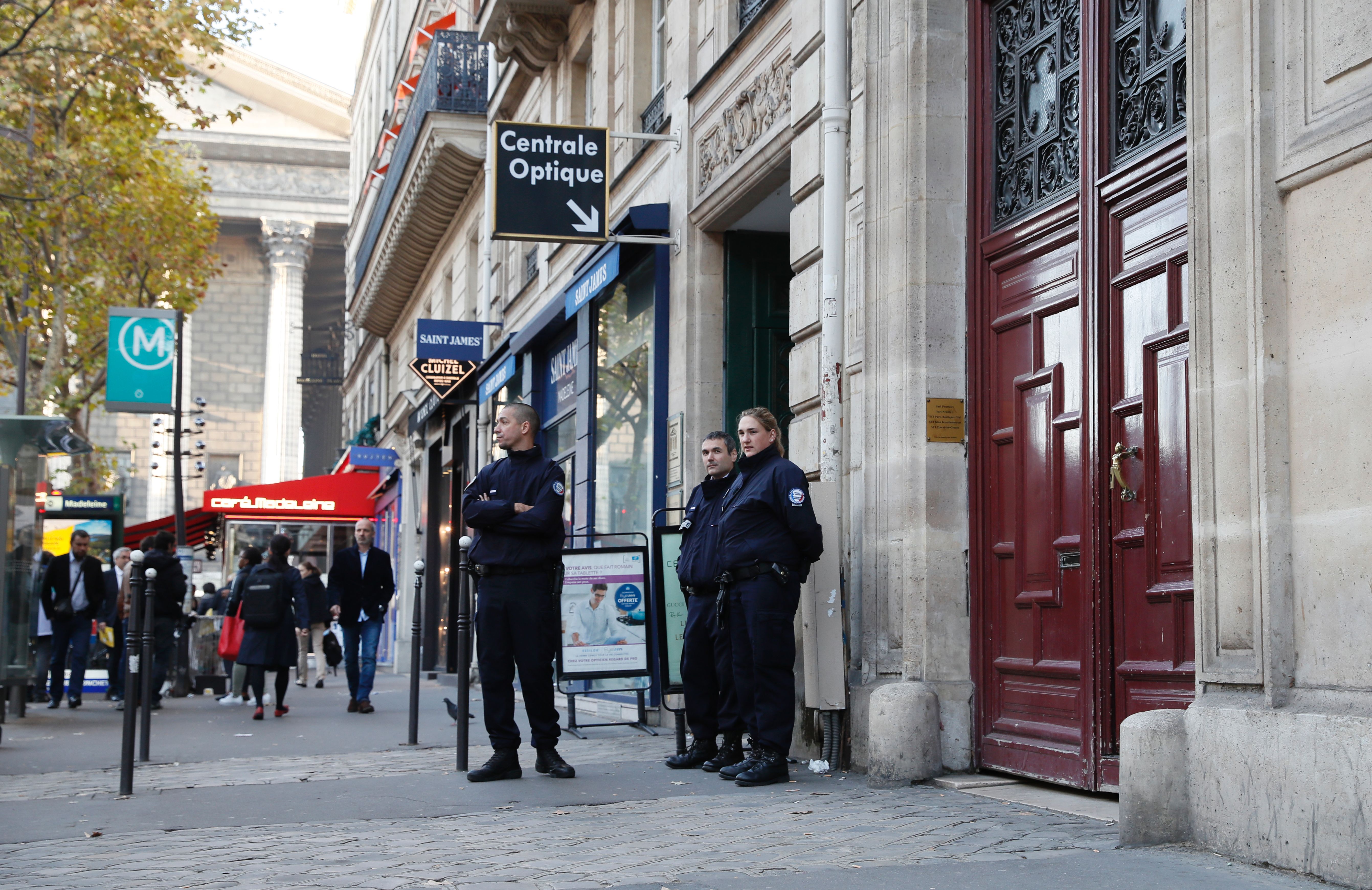 Police officers stand guard at the entrance to a hotel residence at the Rue Tronchet, near Madeleine, central Paris, on October 3, the day of the robbery
