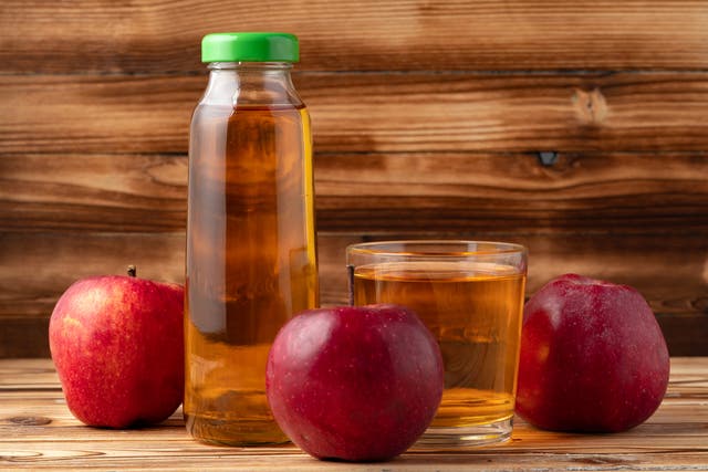 <p>Apple juice in glass bottle with apples on table, close up</p>