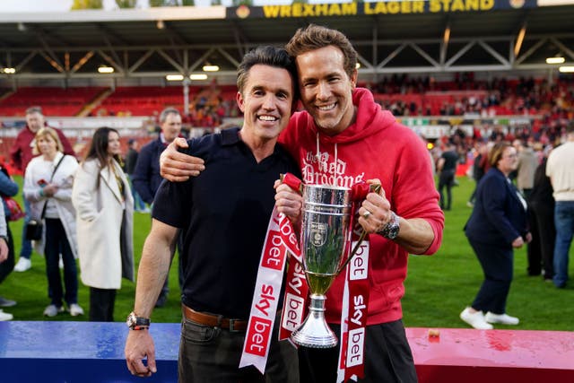 <p>Wrexham co-owners Ryan Reynolds (right) and Rob McElhenney celebrate with the trophy after the Sky Bet League One match at SToK Racecourse, Wrexham. (Martin Rickett/PA)</p>