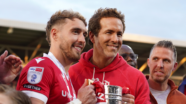<p>Wrexham co-owner Ryan Reynolds, right, and Wrexham's Ollie Palmer pose with trophy at the Racecourse ground in Wrexham, Wales</p>