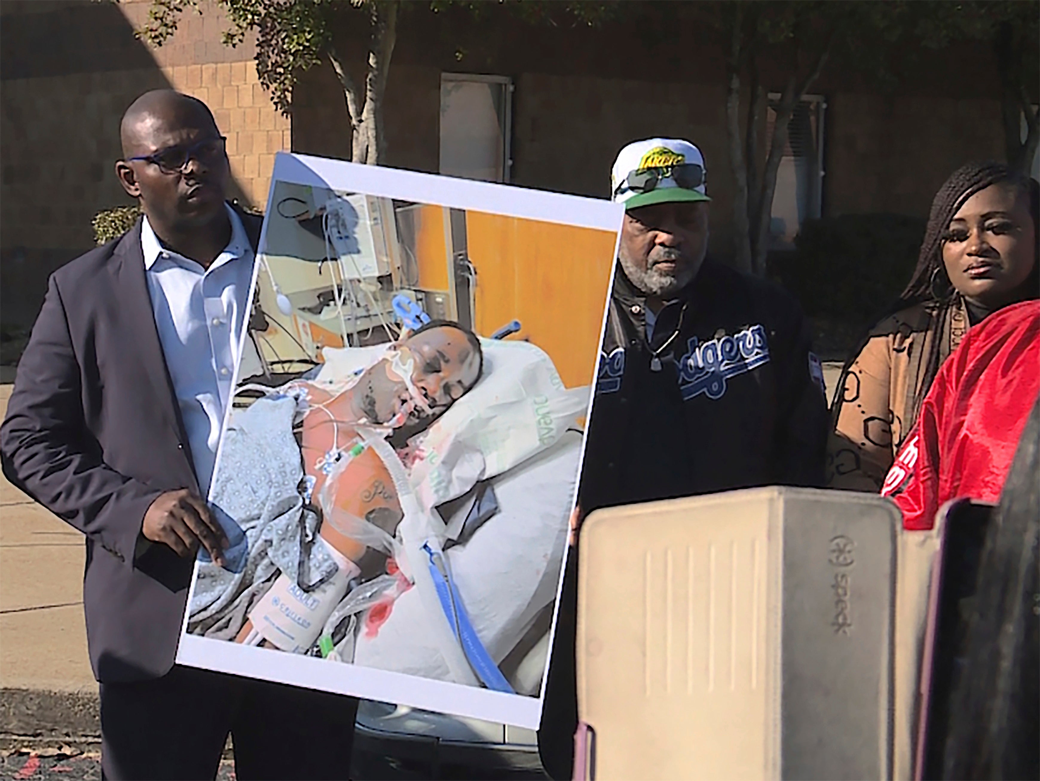 Tyre Nichols' stepfather Rodney Wells, center, stands next to a photo of Nichols in the hospital after his arrest, during a protest in Memphis days after his 2023 death